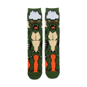 A pair of green socks with a cartoon gremlin on each sock. The gremlin has white hair, orange eyes, and sharp teeth.