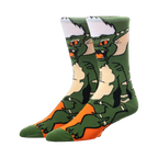 A pair of green and orange crew socks featuring a Gremlin character design. The socks are shown from the side, highlighting the character's face and body.