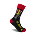 Black crew socks with a red cuff, featuring a tuxedo graphic and colorful groomsmen figures. Text reads 'The Groom'.