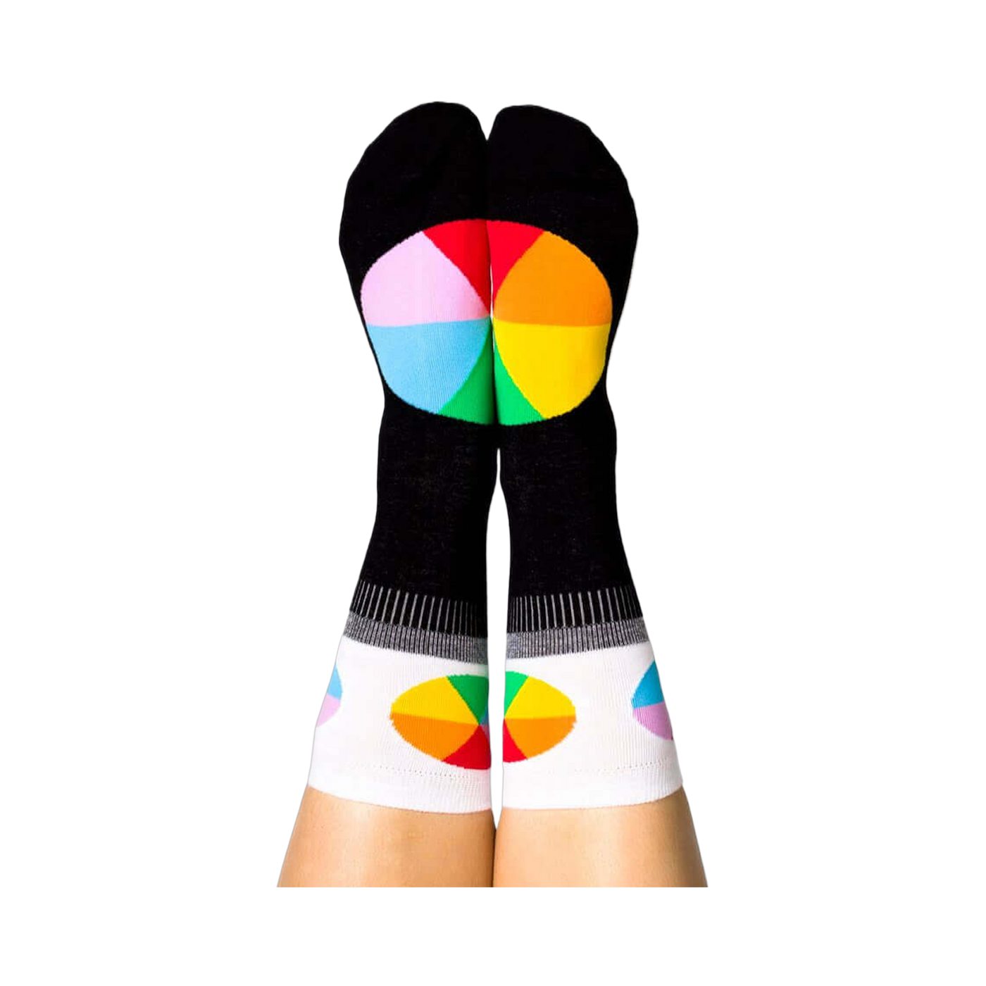 A person's legs with feet up, wearing the black Color Wheel crew socks. The heels show large color wheels, cuffs have smaller ones.