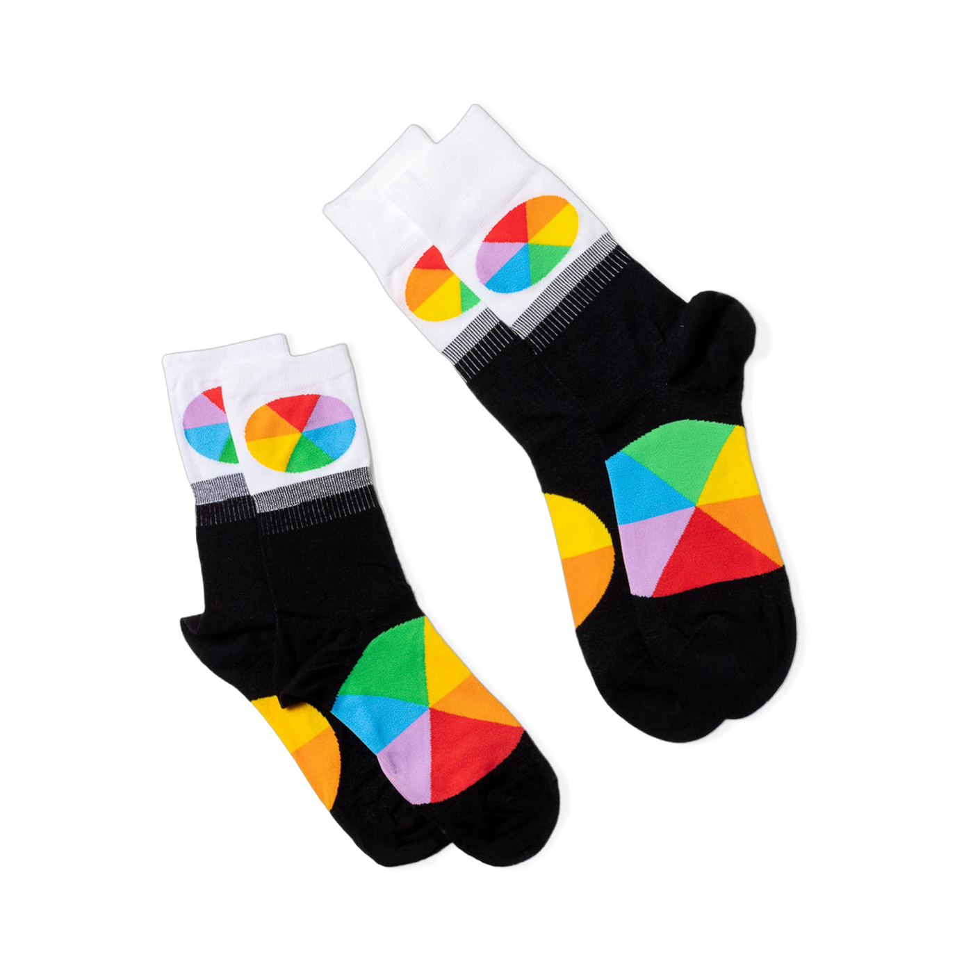 Two pairs of black crew socks with white cuffs and color wheel designs, lying flat and angled differently on a black background.