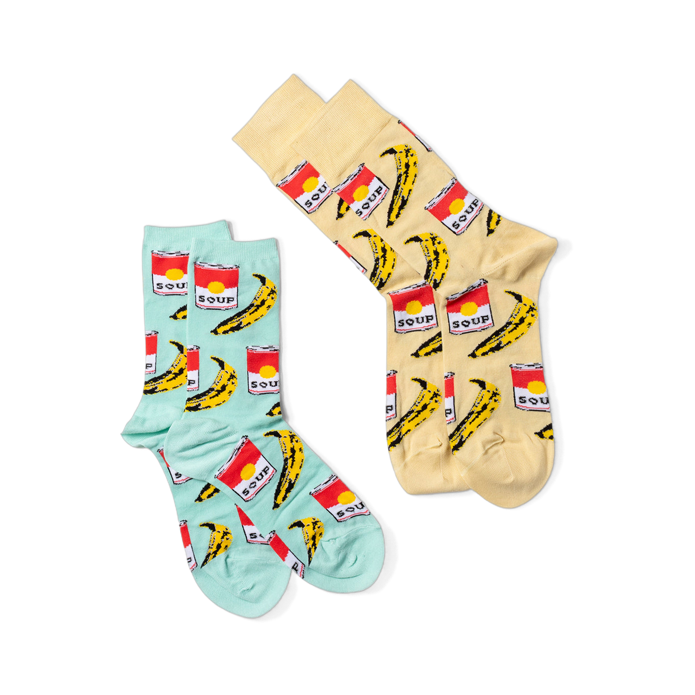 Two pairs of pop art crew socks: one light blue and one light yellow, both featuring red soup cans and yellow bananas, against a black background.