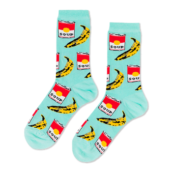 A pair of light blue crew socks with a repeating pop art pattern of red soup cans and yellow bananas, laid flat against a black background.