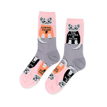 Pair of crew socks in pink and grey, patterned with white cats wearing black and orange shirts with "GURRRL POWER" and "THE FUTURE IS FELINE".