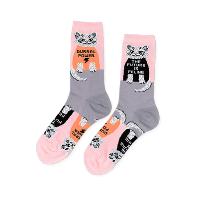 Pair of crew socks in pink and grey, patterned with white cats wearing black and orange shirts with "GURRRL POWER" and "THE FUTURE IS FELINE".