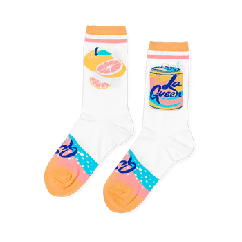 Pair of white crew socks. One has yellow and pink grapefruit, the other a yellow "La Queen" soda can. Pink/blue pattern on heel, orange cuffs/toes.