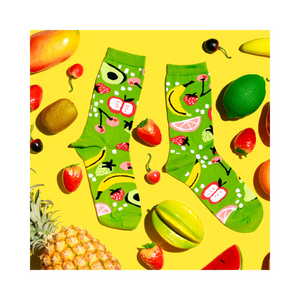 Flat lay of fruit-patterned lime green socks surrounded by fresh and artificial fruits on a vibrant yellow background.