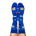 Pair of legs pointing up wearing blue socks covered in retro computer icons including a smiling monitor and floppy disk.