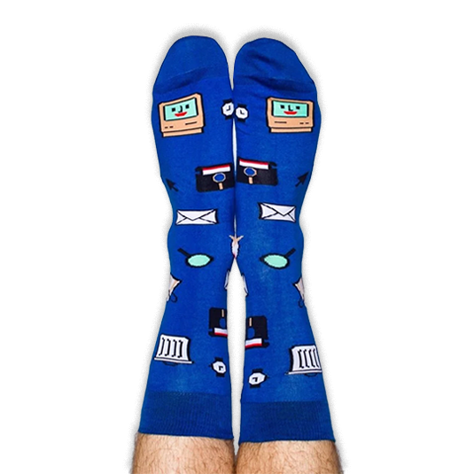 Pair of legs pointing up wearing blue socks covered in retro computer icons including a smiling monitor and floppy disk.