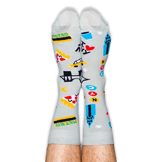 A person wearing light grey NYC patterned socks with their legs pointing straight up against a black background.