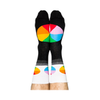 Person standing, wearing black crew socks with white cuffs and colorful, segmented color wheel designs on feet.