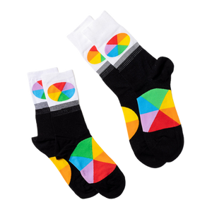 Two pairs of black crew socks with white cuffs and colorful color wheel segments, laid flat on a white surface.