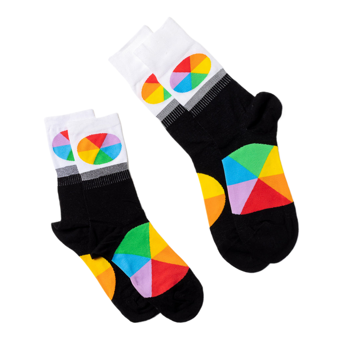 Two pairs of black crew socks with white cuffs and colorful color wheel segments, laid flat on a white surface.