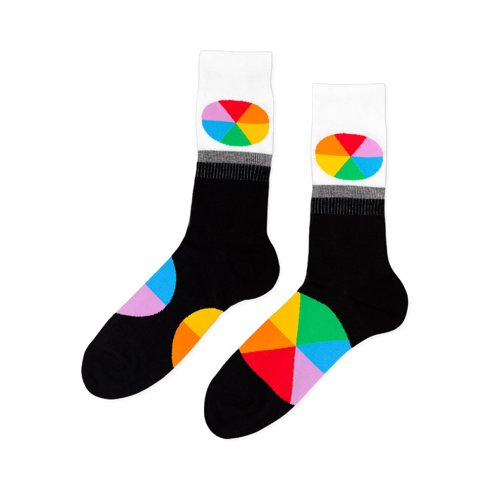 Pair of black crew socks with white cuffs. Each cuff has an oval, rainbow-segmented color wheel design. Large color wheel segments on the foot.