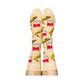Person wearing Pop Art socks with red soup cans and yellow bananas, shown on legs from the calves down.
