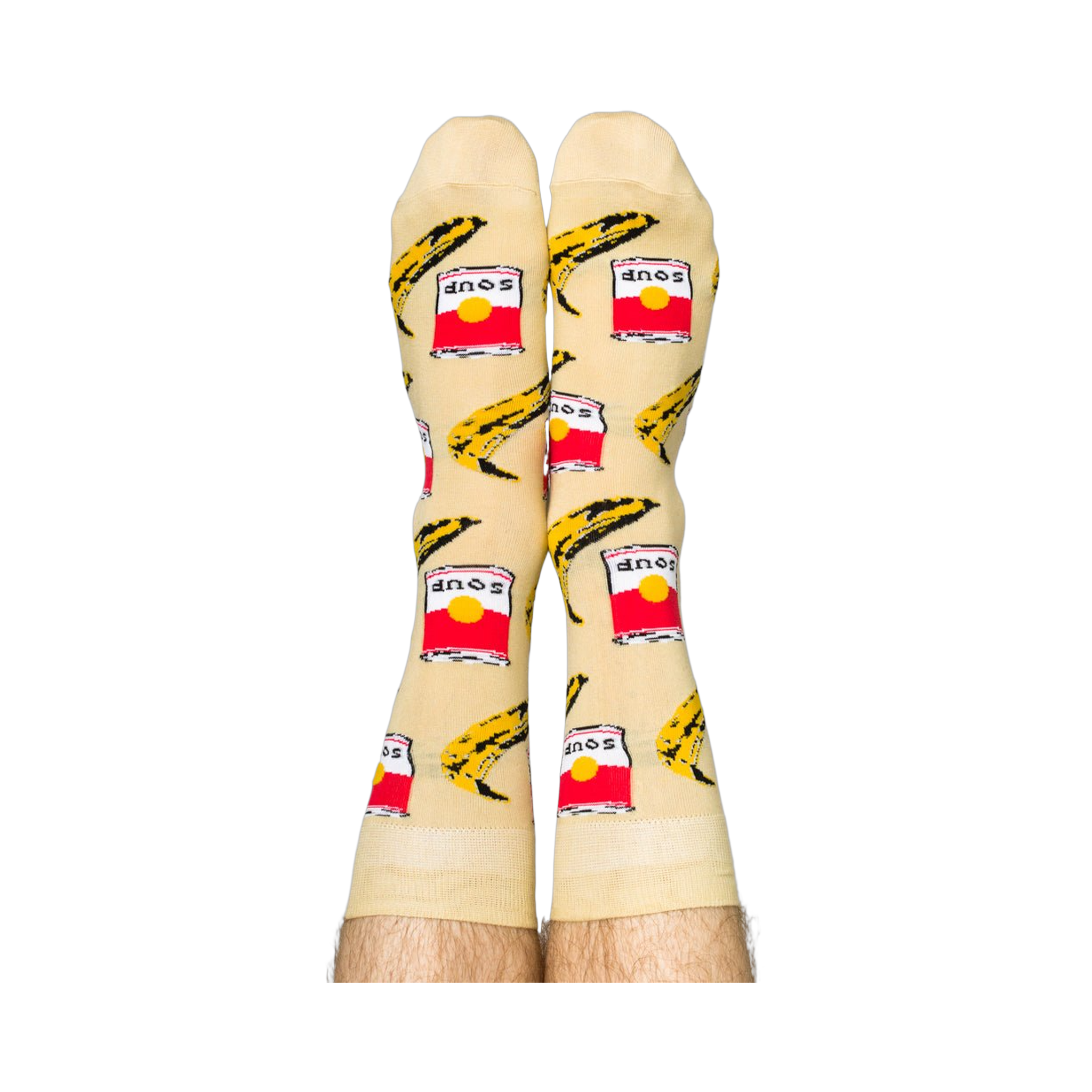 Person wearing Pop Art socks with red soup cans and yellow bananas, shown on legs from the calves down.