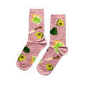 A pair of pink crew socks patterned with avocado toast, sliced and whole avocados, and a knife, on a light pink background.