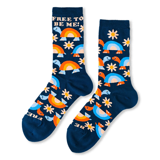 Navy blue crew socks covered in smiling turtles and white daisies with FREE TO BE ME text near the cuffs.