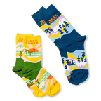 Flat lay of the yellow and green West Coast socks next to a blue and navy version of the same scenic design.