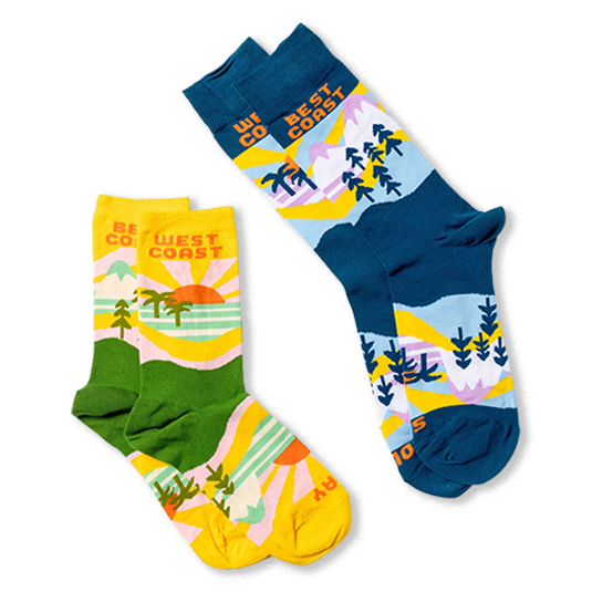 Flat lay of the yellow and green West Coast socks next to a blue and navy version of the same scenic design.