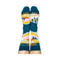 A person wearing the West Coast Best Coast socks, soles up. The 'STAY GOLD' text is visible on the bottoms.