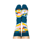 A person wearing the West Coast Best Coast socks, soles up. The 'STAY GOLD' text is visible on the bottoms.