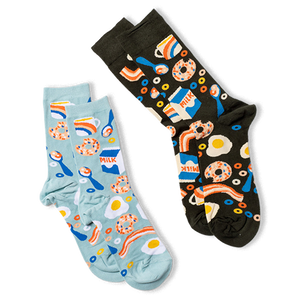Two pairs of breakfast pattern crew socks: one dark background, one light blue, laid diagonally on a white surface.