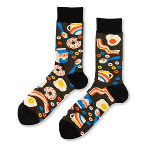 Pair of crew socks with a black background covered in a pattern of fried eggs, bacon, donuts, milk cartons, and coffee cups.