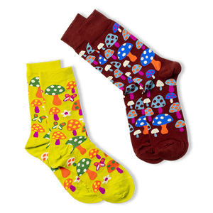 Two pairs of patterned crew socks shown on a black background. A yellow pair with mushrooms and butterflies, and a burgundy pair with blue and orange mushrooms.