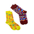 Two pairs of patterned crew socks shown on a black background. A yellow pair with mushrooms and butterflies, and a burgundy pair with blue and orange mushrooms.