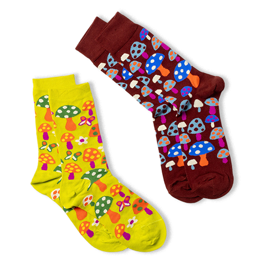 Two pairs of patterned crew socks shown on a black background. A yellow pair with mushrooms and butterflies, and a burgundy pair with blue and orange mushrooms.