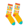 Pair of crew socks in yellow with a repeating pattern of books and glasses on a bookshelf in red, teal, and white.