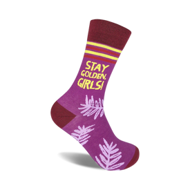 purple crew socks with dark red cuff, yellow toe, and yellow "stay golden girls!" lettering on front and pink palm leaf pattern on back.  