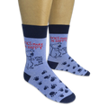 Person wearing light blue socks featuring navy paw prints, a cartoon dog, and the phrase Dogs Make Me Happy You Not So Much.
