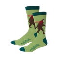 Pair of crew socks featuring a light green background, teal cuffs, and a brown Bigfoot wearing a red scarf.