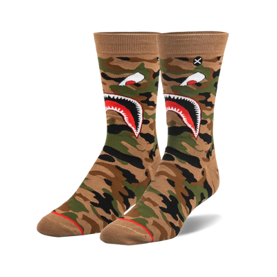 Pair of crew socks with brown, green, and black warplane camouflage. Features a white shark mouth design with red details.