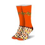 Pair of crew socks in orange, brown, and cream. Features Reese's Pieces logo and polka dot pattern.