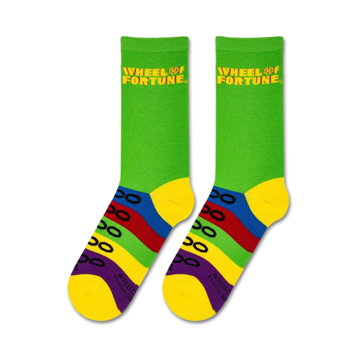 A pair of green socks with a Wheel of Fortune logo in yellow on the top cuff. Under the logo are four horizontal colored stripes in red, orange, yellow, and blue.