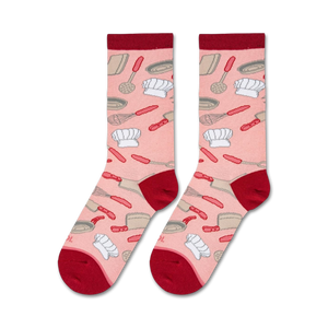 A pink background fabric with repeating pattern of chef hats, spatulas, and whisks in gray and red.