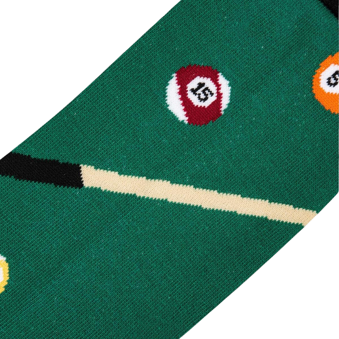 A green pool table sock with a pool cue and billiard balls in the background.