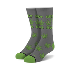 Pair of gray crew socks with green cannabis leaf pattern and 'Best Buds' text.  Features cartoon marijuana leaves with faces.