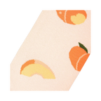 Close-up angled view of a light peach sock fabric, showing a whole peach and a peach slice in detail.