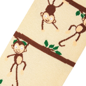 A close up of a pair of brown and cream colored socks with a pattern of monkeys hanging from tree branches.
