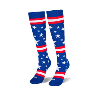 Two knee-high blue socks standing upright on a black surface, showing scattered white stars and red and white stripes.