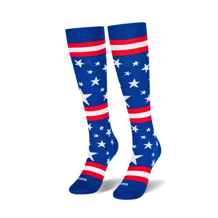Two knee-high blue socks standing upright on a black surface, showing scattered white stars and red and white stripes.