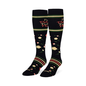 Angled studio shot of black knee-high socks displaying yellow and pink roses with retro striped bands around the calves.