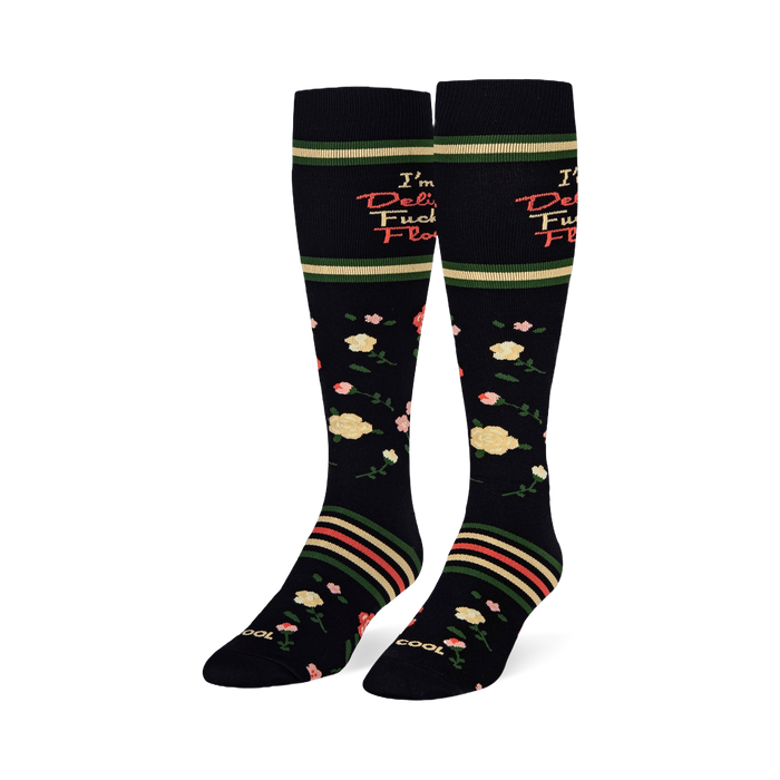 Angled studio shot of black knee-high socks displaying yellow and pink roses with retro striped bands around the calves.