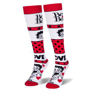 Angled studio shot of Betty Boop knee-high socks standing upright, highlighting the bold red polka dot stripes.