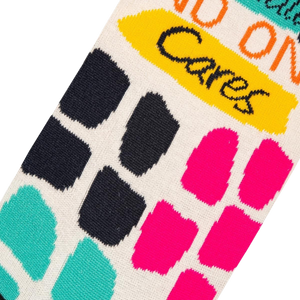 A close up of a pair of socks with a white background and colorful squares in a graph-like pattern. The squares are blue, green, pink, and black. The word 