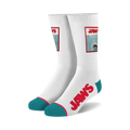 Pair of white crew socks.  Feature a Jaws movie poster image and red 'JAWS' text. Teal accents at the heel and toe.